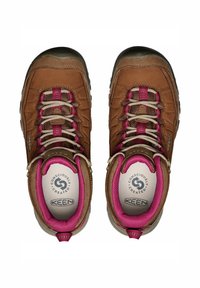 Braune Wanderschuhe mit pinken Akzenten, ausgestattet mit einem strukturierten Obermaterial, beigen Schnürsenkeln und gepolsterten Einlegesohlen. Für den Einsatz im Freien konzipiert, mit einer robusten Sohle.