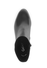 Bottine en cuir noir avec un bout arrondi et une fermeture éclair sur le côté, vue d'en haut sur un fond blanc.