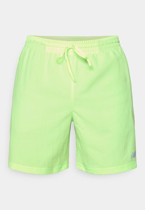 Shorts de sport vert clair avec taille élastique, cordon de serrage et petit logo gris sur le bas de la jambe gauche.