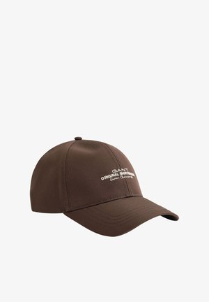 Brown baseball cap with curved brim and white text logo reading "GANT Original Shirtmakers Genuine. Classic est 1949" on front.