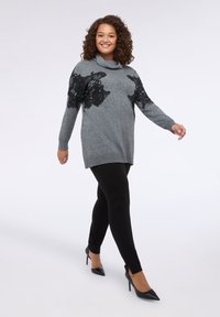Pulover gri cu detalii din dantelă neagră pe umeri, guler înalt, asociat cu colanți negri și pantofi cu toc ascuțit negri. Textură netedă pe toată suprafața.