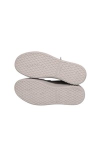 Baskets en caoutchouc grises avec une semelle texturée à motif hexagonal, dotées d'un intermédiaire blanc et d'une légère élévation au niveau du talon pour un soutien supplémentaire.