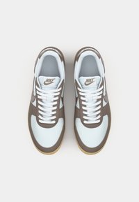 Nike tenisice imaju svijetloplavu gornjište s smeškastim detaljima, bijele vezice i gumeni potplat. Dizajn uključuje glatku teksturu i detalj s logotipom.