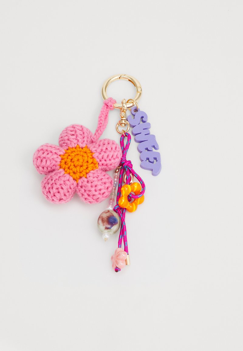 Breloc de chei croșetat în formă de floare roz cu centru galben, inel din metal aurit și accesorii colorate, inclusiv un charm violet cu mesajul "Sweet" și diverse mărgele.