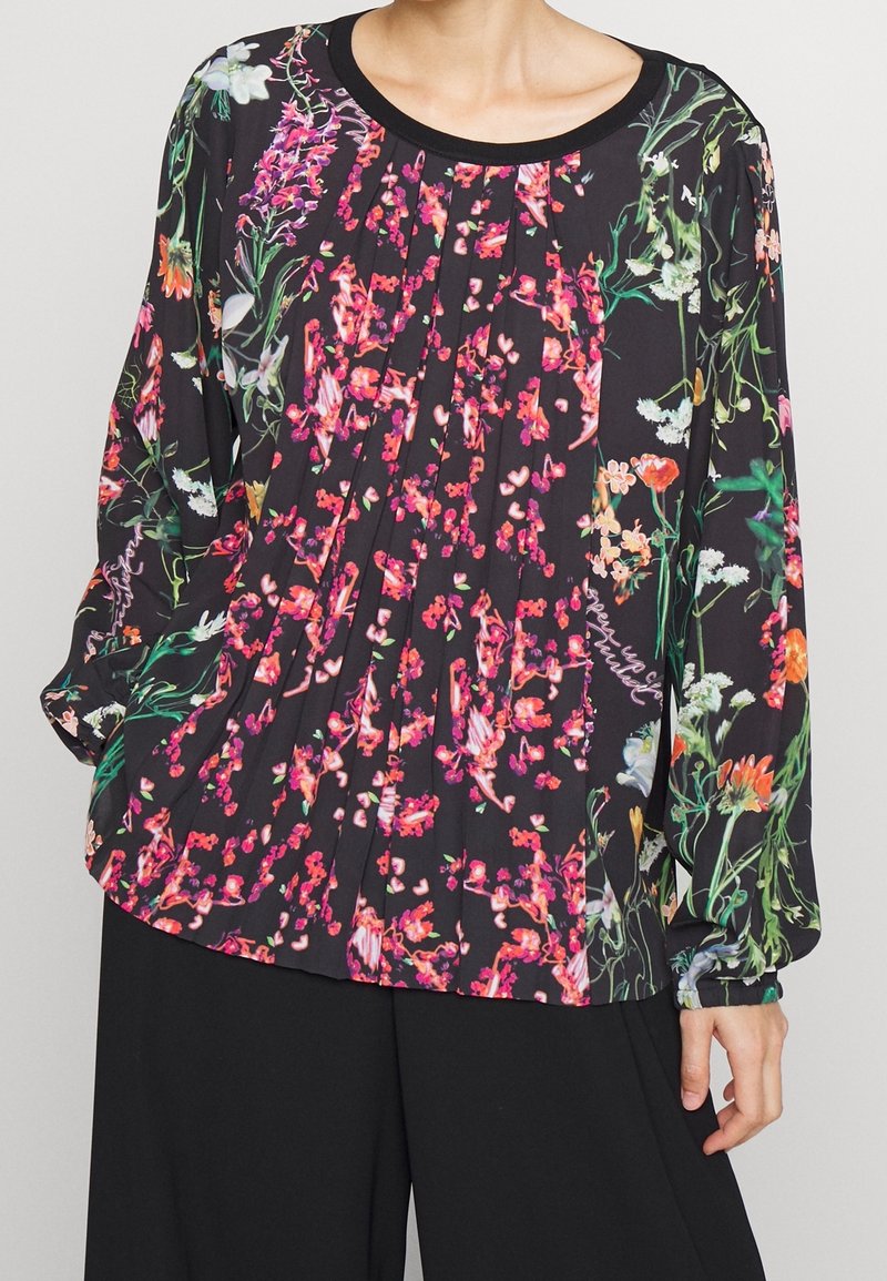 Schwarze Bluse mit floralem Muster in Pink, Weiß und Grün. Verfügt über ein plissiertes Design und lange Ärmel mit elastischen Bündchen. Rundhalsausschnitt.