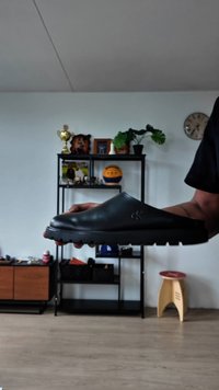 Zapato negro tipo mocasín con una textura suave, punta redonda y suela robusta. Presenta un logo sutil en el costado.