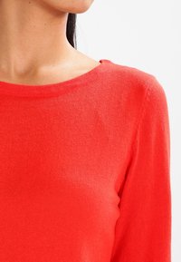 Rode gebreide trui met een bootnek, lange mouwen en een zachte textuur. Heeft een slim fit en een gladde afwerking zonder versieringen.