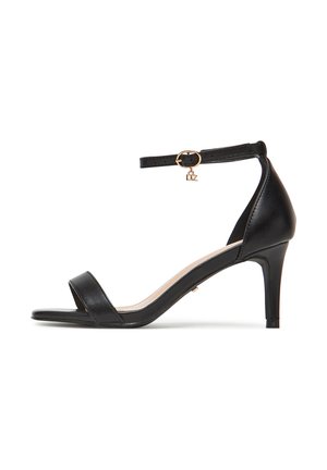 Sort læder sandal med hæl, der har en tynd ankelrem med en guldbøjle og vedhæng, åben tå-design og en slank stiletto hæl.