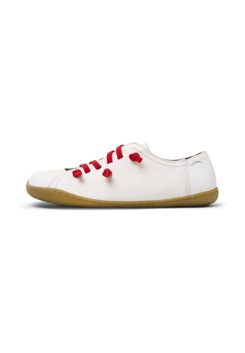 Chaussure en cuir blanc avec des lacets en tissu rouge, à profil bas, avec un bout arrondi et une semelle en caoutchouc tan flexible. Design minimaliste sans marque visible.