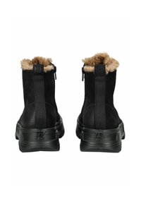 Botas negras hasta el tobillo con parte superior texturizada, cuello forrado de piel y cremalleras traseras. Presentan una suela de goma negra sólida con la marca en la parte posterior.