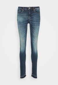 Jeans ajustados en denim azul oscuro, con un desvanecimiento gradual, cinco bolsillos y dobladillos deshilachados para un aspecto desgastado.