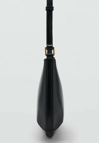 Black leather crossbody bag with adjustable strap and gold-tone buckle, shown from a side profile on a plain background.