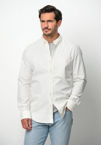 Witte lange mouwen blouse van katoen, met een enkele borstzak en een klassieke kraag, gecombineerd met lichtblauwe jeans.