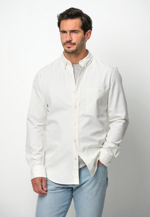 Witte lange mouwen blouse van katoen, met een enkele borstzak en een klassieke kraag, gecombineerd met lichtblauwe jeans.
