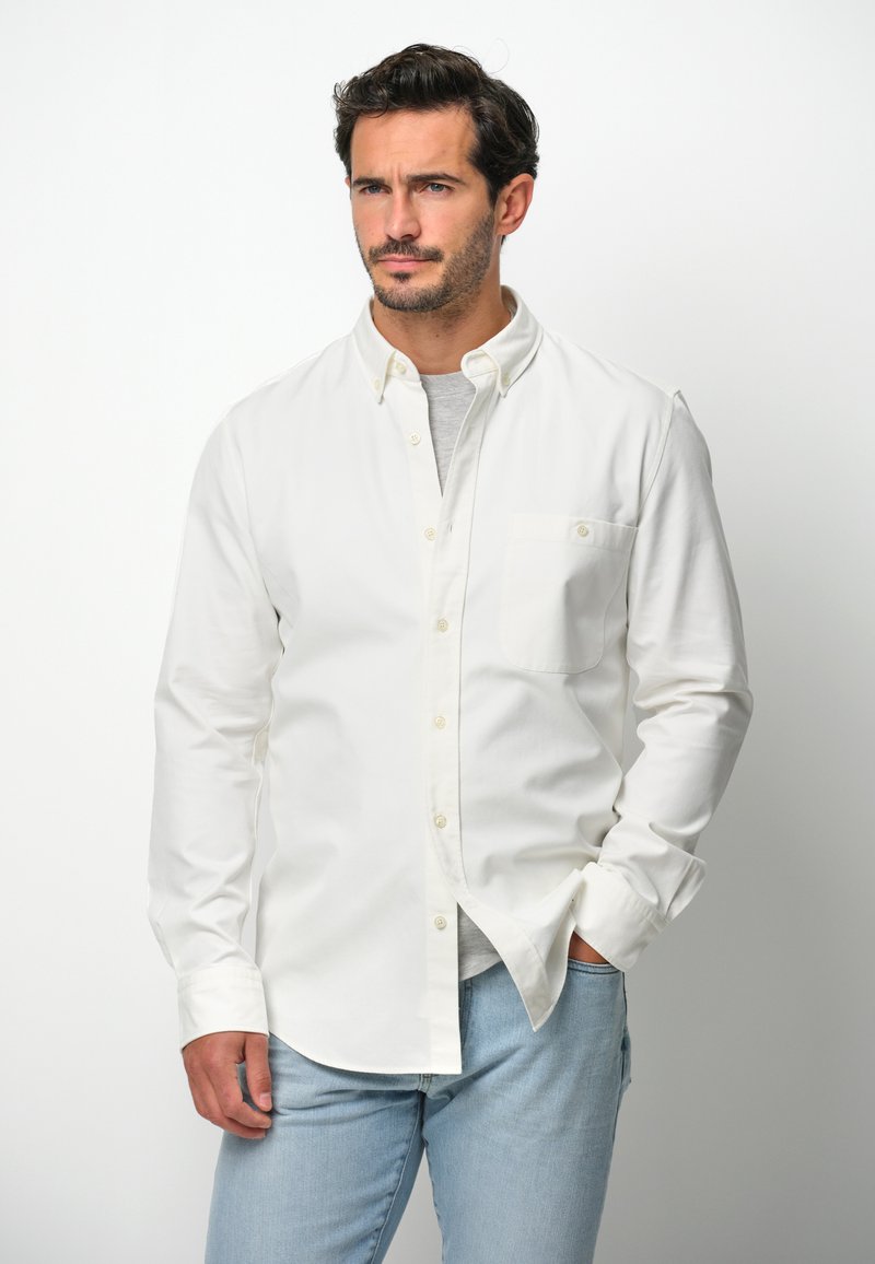 Witte lange mouwen blouse van katoen, met een enkele borstzak en een klassieke kraag, gecombineerd met lichtblauwe jeans.