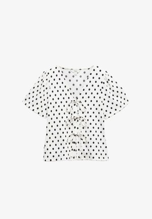 Weißes Oberteil mit schwarzen Punkten, tiefem V-Ausschnitt und kurzen Puffärmeln. Mit drei gebundenen Akzenten an der Vorderseite. Weiche Textur.