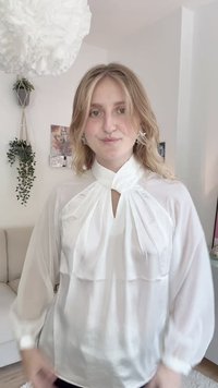 Weiße Bluse mit hohem Kragen, Vorderfalten und langen Puffärmeln. Durchscheinender Stoff mit glatter Textur. Minimalistisches Design, ohne Muster.