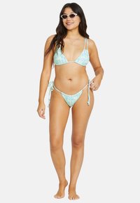 Trekantbikini i lyseblå med blomstermønster. Snører i sidene av underdelen, justerbare stropper på toppen. Glatt, elastisk stoff.