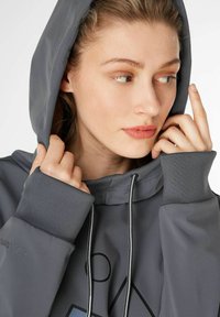Grauer Kapuzenpullover mit Kordelzugkapuze, gerippten Bündchen und bedruckten geometrischen Designs. Weicher Stoff mit Seitennähten.