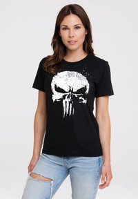 Black cotton t-shirt featuring a large white skull graphic. The design includes splatter accents and a crew neckline. Paired with distressed light blue jeans.