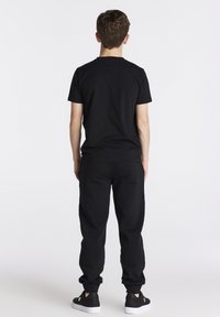 Zwart T-shirt met korte mouwen, gecombineerd met bijpassende zwarte sweatpants, met een comfortabele pasvorm en subtiele textuur. Afgerond met zwarte sneakers.