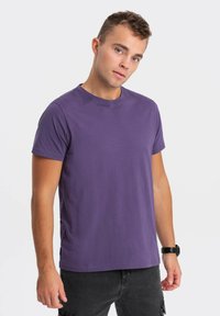 Lilla bomulds T-shirt med rund hals og korte ærmer. Stoffet ser glat og let ud, hvilket giver en afslappet pasform.
