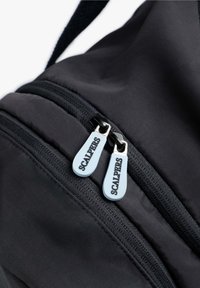 Bolsa de tela negra con textura suave, cremalleras dobles con tiradores azul claro etiquetados como "SCALPERS" y costuras resistentes a lo largo de las juntas.