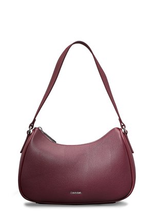 Sac d’épaule en cuir marron foncé avec forme incurvée, une seule bandoulière, fermeture éclair argentée et petit logo Calvin Klein au centre avant.