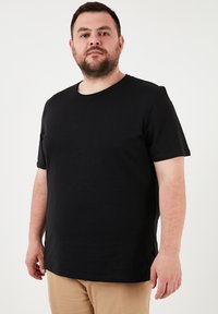 Černé tričko s krátkým rukávem vyrobené z měkké bavlny, s kulatým výstřihem a volným střihem. Minimalistický design bez výrazných vzorů.