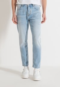 Vaqueros de denim azul claro con un corte relajado, que presentan un ligero desgaste, cinco bolsillos, trabillas para cinturón y un corte recto.