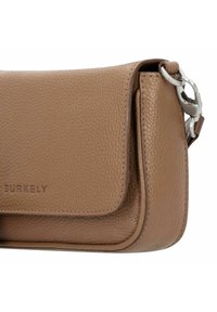 Borsa a tracolla in pelle color tan con superficie texturizzata, patta pieghevole, hardware in argento e logo impresso davanti. Forma rettangolare compatta.