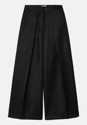Pantaloni neri a gamba larga con una texture liscia, caratterizzati da una vita alta, pieghe e tasche laterali. Senza dettagli di chiusura visibili.
