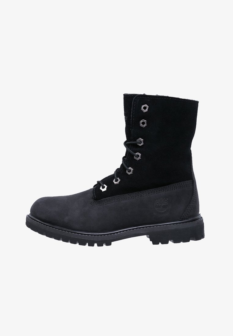 Botte cheville à lacets en cuir noir et daim, avec semelle robuste et œillets métalliques, embossée sur le côté d'un logo rond.