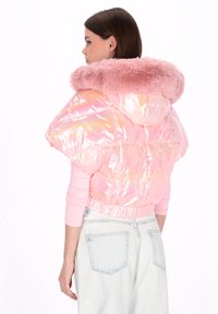 Jasnoróżowa pikowana kurtka z błyszczącym, opalizującym wykończeniem i miękkim, różowym kapturem z futerka sztucznego. Krótki fason z elastycznym paskiem w talii.