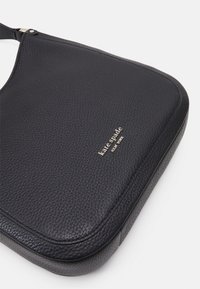 Sort læder skuldertaske med en pebble-tekstur, buet form og guld logo detalje. Sikret strop for nem bæring.