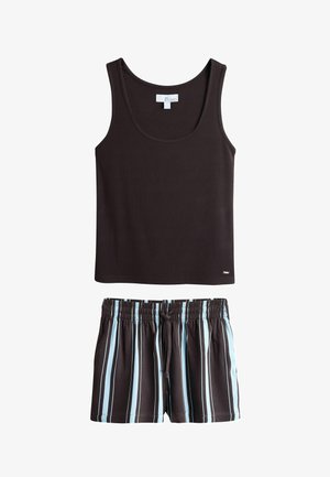 Vrouw staand binnen, draag een zwart hemdje en zwarte korte broek met blauw-witte verticale strepen.