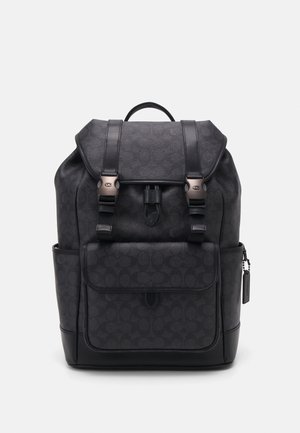 Mochila preta com uma superfície texturizada, apresentando um fecho de aba, duas alças ajustáveis, bolso frontal e detalhes em metal.