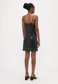 Fekete flitteres miniruha, testhez simuló fazonú, vékony spagetti pántokkal és texturált hullámos mintával. Sima anyagú és egyenes szegélyű.