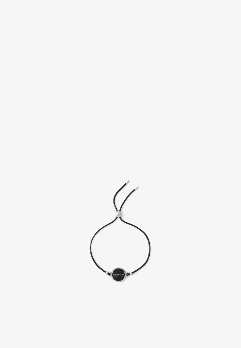 Bracelet en cuir noir avec un accent en argent rond arborant un logo en relief, sangle ajustable, design minimaliste et finition épurée.
