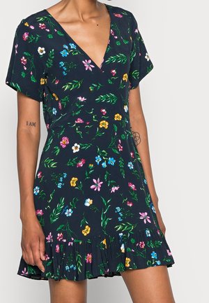 Sukienka w kwiaty w kolorze granatowym, z dekoltem w kształcie litery V, krótkimi rękawami i falbaną na dole. Materiał jest lekki o gładkiej fakturze.
