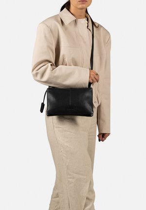 Schwarze Leder-Crossbody-Tasche mit Reißverschluss, ausgestattet mit einer glatten Textur und rechteckiger Form. Der Trageriemen ist an beiden Seiten befestigt.