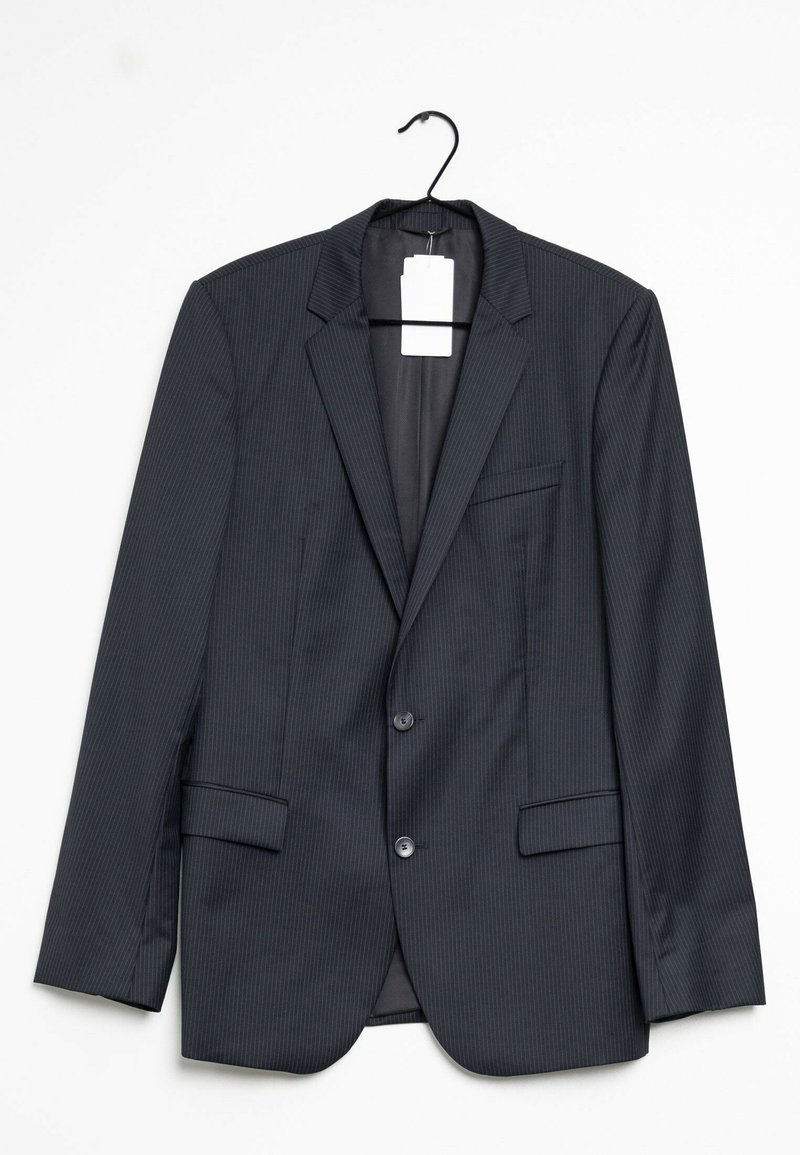 Blazer nero a righe, con rever a punta, due tasche anteriori e due bottoni. Sospeso a un gancio nero, etichetta visibile all'interno.