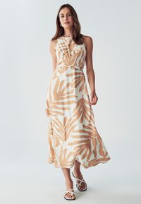 Maksi obleka iz belega blaga z rjavimi listnatimi vzorci, ima prilegan bodice in razširjen krilo. V kombinaciji z belimi ravnimi sandali.