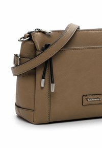Beige leather handbag with a textured finish, featuring a crossbody strap, silver metal accents, and zip closure with black drawstrings.