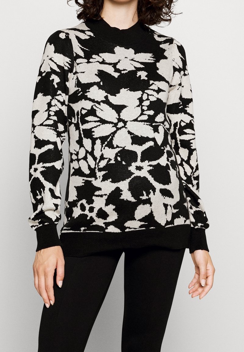 Svart och krämfärgad blommig mönstrad tröja med rund halsringning, långa ärmar och ribbade muddar, som bärs med svarta leggings.