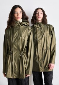 Green waterproof jackets with adjustable drawstrings at the waist, featuring large pockets and a high collar design. Smooth, shiny fabric.