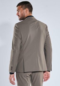 Light grey suit jacket made of smooth fabric, featuring a single vent at the back and decorative buttons on the cuffs.