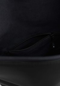 Interno di una borsa di tessuto nero con una tasca con zip. La fodera è liscia e opaca, con una texture discreta e senza motivi visibili.
