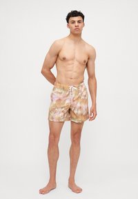 Herren-Schwimmshorts mit Batikmuster in sanften Pastellfarben von Pink, Gelb und Grün. Leichter Stoff, elastischer Bund mit Kordelzug und knielanger Schnitt.