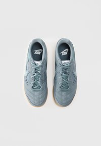 Nike sneakers with a light blue textile upper, textured accents, lacing system, white logo on tongue, and gum rubber outsole.